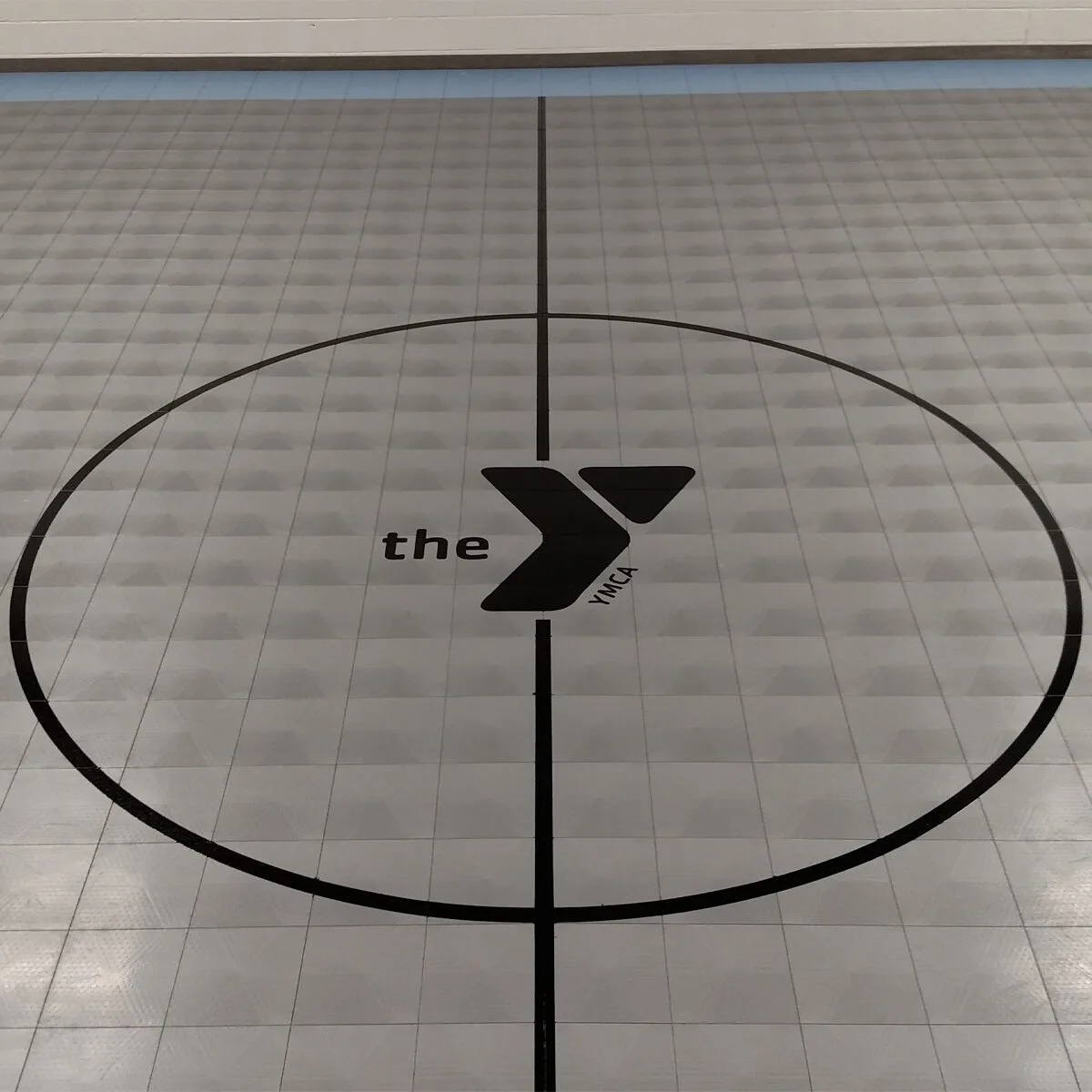 The YMCA logo on black and gray court flooring