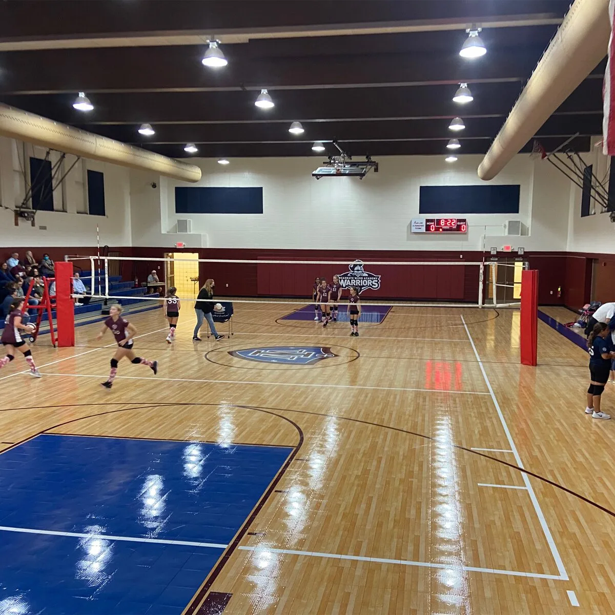Girls' volleyball game in a school gymnasium with a volleyball net