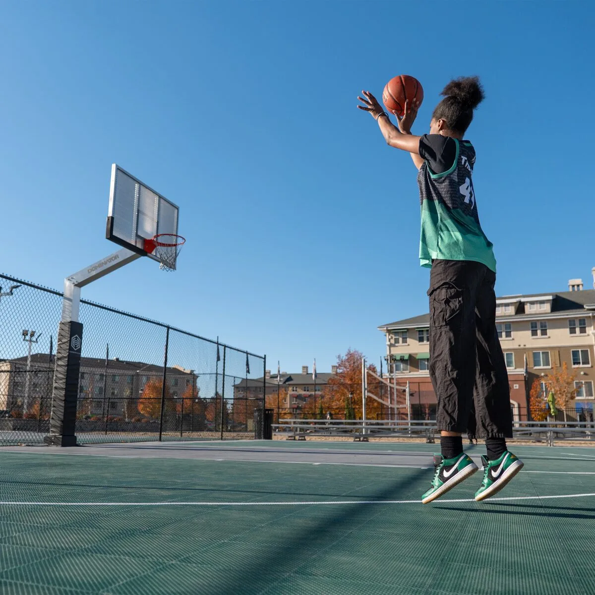 A girl playing basketball on a facility's outdoor basketball court