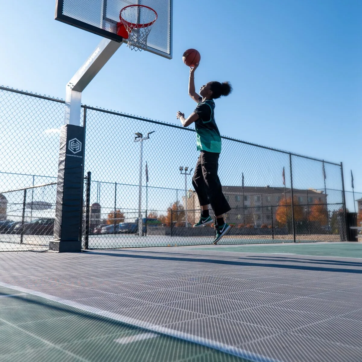 Female basketball player throwing a basketball into a hoop on an outdoor court