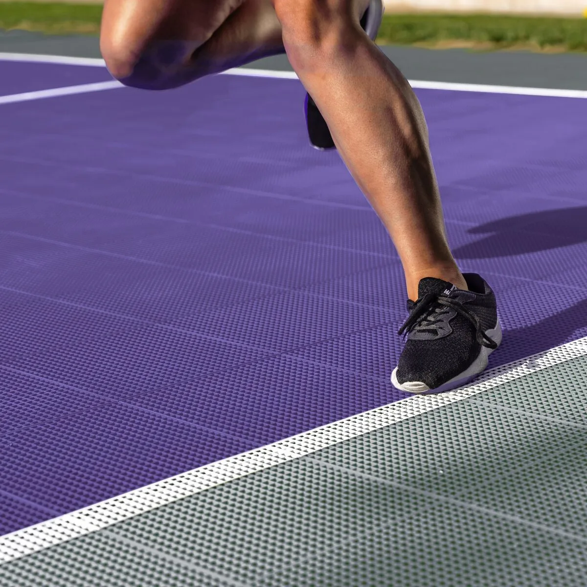 A black sneaker on a purple and gray game court surface