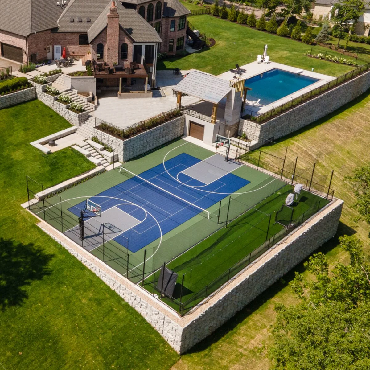 An outdoor residential multi-sport court with an in-ground pool and patio